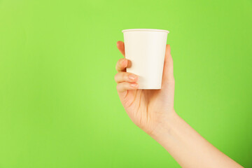 Woman holding paper cup on green background, closeup. Mockup for design