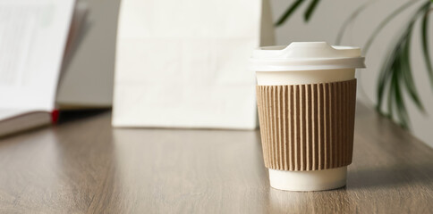 Paper cup on wooden table in cafe, closeup. Mockup for design