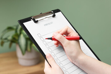 Woman filling Checklist with marker indoors, closeup