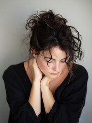 Fototapeta premium Thoughtful young woman with messy dark hair gazing down in a contemplative mood showcasing natural beauty : Generative AI