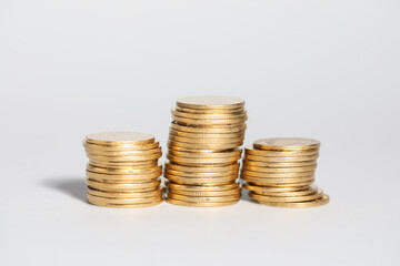 Many stacked coins on light grey background, closeup