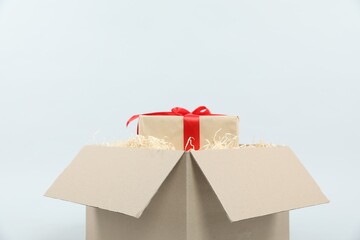 Parcel with gift box on light background, closeup
