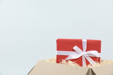 Parcel with gift box on light background, closeup
