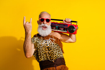 Photo of funny funky barbarian guy dressed leopard fur listening boom box showing hard rock sign isolated yellow color background