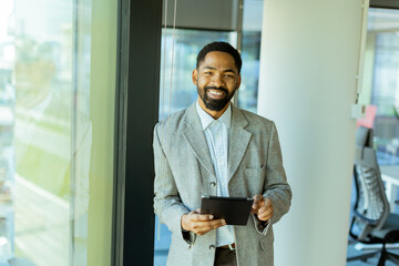 Fototapeta premium Professional man contemplating future while holding tablet in modern office setting