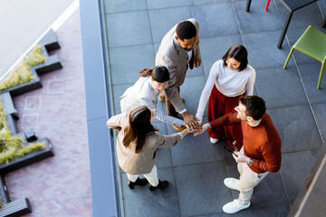 Group of friends sharing a joyful moment of connection and teamwork outdoors in bright sunlight