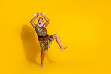 Full length photo of strong paleolitic human wear leopard skin dancing rising animal bone emtpy space isolated yellow color background