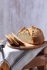 Homemade Irish soda bread cut into pieces and knife on wooden background.