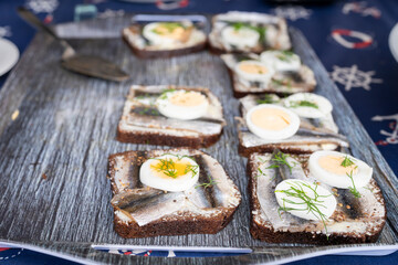 Sandwich with spiced sprat and sliced boiled quail egg on the slice of rye bread. Canned fish is Estonian national food. Concept of food and organic farm products.