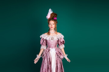 Woman in a pink baroque-style dress with a feathered hairstyle against a green background...