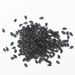 Black sesame seeds scattered on a white background macro top view