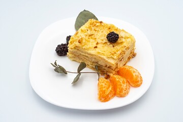 A piece of Napoleon cake with blackberries on a white plate. Dessert.