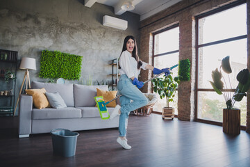 Fototapeta premium Young woman cleaning a bright modern living room and enjoying the day