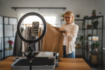 mature woman stand and show beige sweater in front camera set up