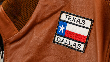 Close-up of a Texas Dallas embroidered patch on a brown leather jacket, showcasing regional pride...