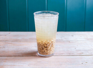 Refreshing Iced Barley Water with ice cube served in glass isolated on wooden background side view...