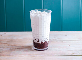 Iced red bean with coconut milk with ice cube served in glass isolated on wooden background side...