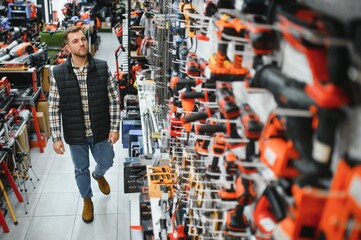 A man in a hardware store choosing a tool