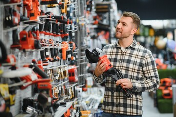 A man in a hardware store choosing a tool