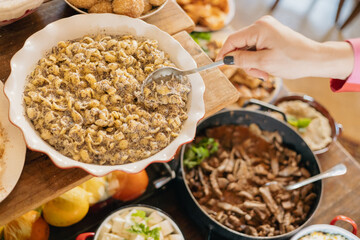 Woman serving poppy seed pasta from buffet table at a party