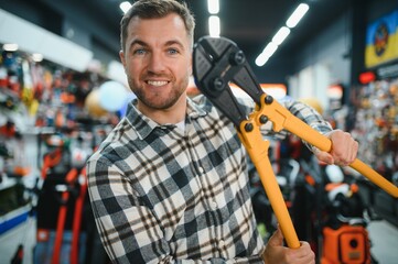 A man in a hardware store choosing a tool