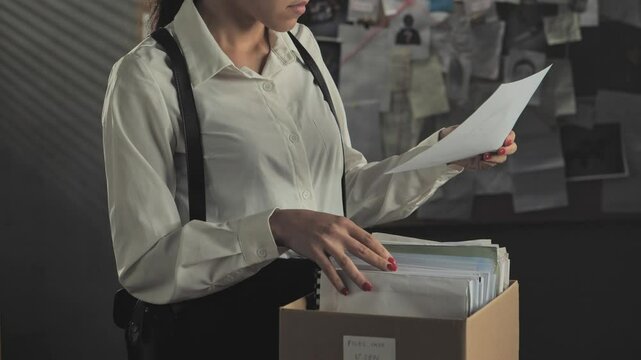 female police detective browsing identikit file,woman investigator working on criminal case browses crime papers standing in office