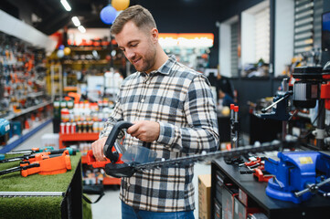a man chooses a brushcutter in a hardware store