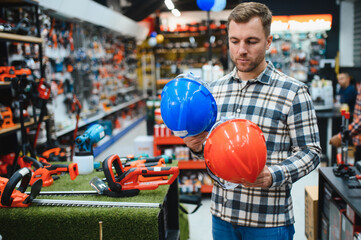 A man in a hardware store choosing a tool