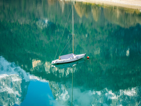 Aerial drone view of Lake Molveno, beautiful lake in Italy. Lake in dolomites from drone in winter. Lake Molveno in Italy. Sailboat, yacht on crystal clear lake in the Brenta Dolomites