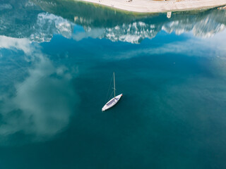 Aerial drone view of Lake Molveno, beautiful lake in Italy. Lake in dolomites from drone in winter. Lake Molveno in Italy. Sailboat, yacht on crystal clear lake in the Brenta Dolomites