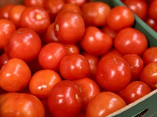 Fresh red tomatoes in container baskets, offered for sale at the supermarket's vegetable stand, showcase organic, vegetarian and healthy food. Close-up