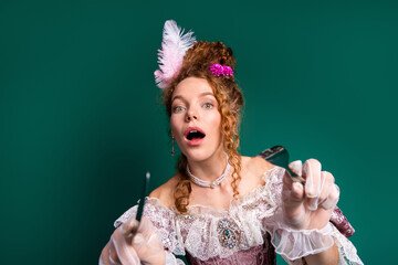 Elegant woman in historic baroque costume posing with gloves on green background
