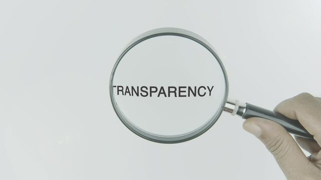 Transparency text or word highlighted by a magnifying glass in a hand on a white background, symbolizing openness and clarity