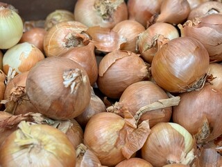Pile of an yellow onion sale in box in vegetable stand display at supermarket show organic food, vegetarian food, healthy food. Close-up