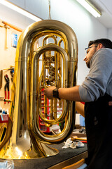 Luthier repairing tuba in musical instrument workshop