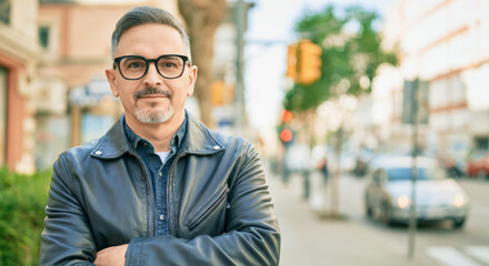 Obraz premium Caucasian mature male in leather jacket on busy urban street with crossed arms