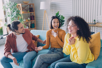 Young diverse friends enjoying happy moments indoors in a stylish living room setting, showcasing...