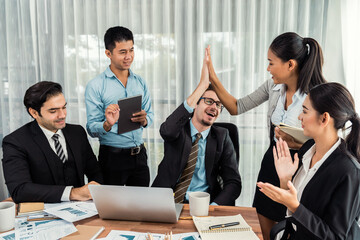 Group of happy businesspeople in high five gesture and successful efficient teamwork. Diverse race office worker celebrate after made progress on marketing planning in corporate office. Meticulous