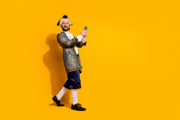 Man dressed in vintage nobleman outfit takes a selfie against vibrant yellow background