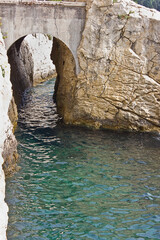 steep rocky seashore with an arch in the cliff