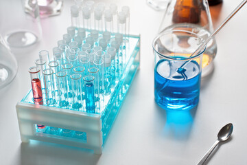 Lab table with test tubes stand and blue liquid in beaker, chemical analysis concept