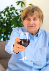 Old woman drinking wine. Selective focus.