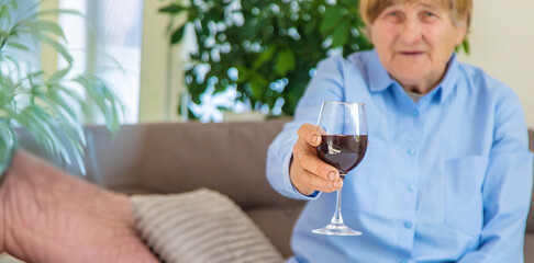 Old woman drinking wine. Selective focus.