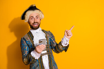 Nobleman in historical costume using modern smartphone on yellow backdrop