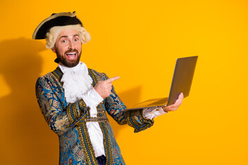 Man in vintage noble costume holding laptop on a bright yellow background