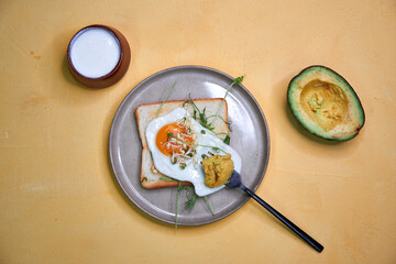breakfast scrambled eggs with toasted bread with herbs and avocado on a ceramic plate top view