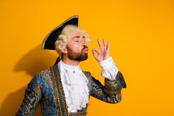 Young man dressed as a nobleman gesturing approval on a yellow background
