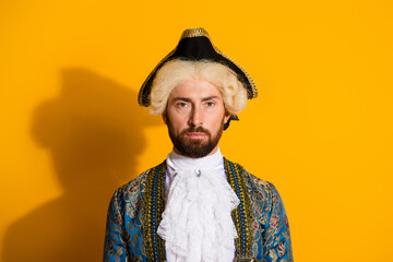Young man in an elegant historic costume posing against a yellow background