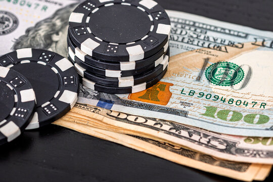 Stacks of poker chips with money on black background