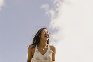Carefree Asian Woman Laughing Under Blue Sky